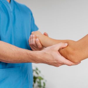 side-view-male-osteopathic-therapist-checking-female-patient-s-elbow-joint-movement